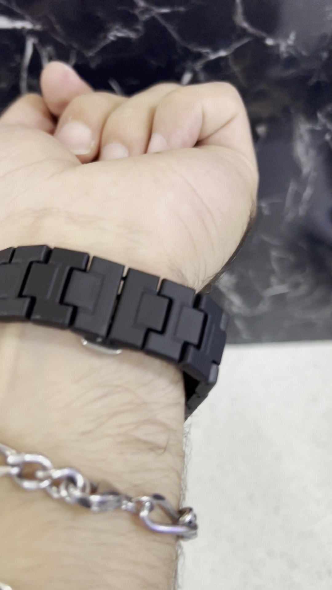 Correa de eslabones mate y cierre del reloj negro puesto en la muñeca (foto real)