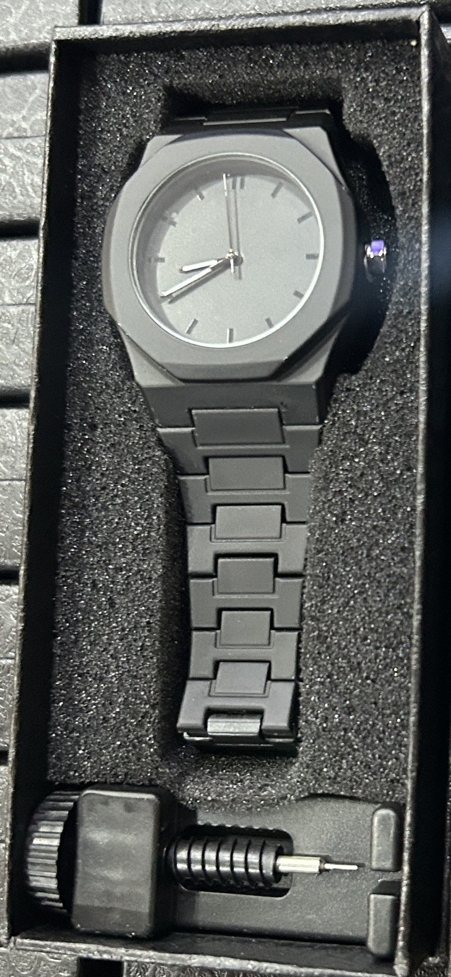 Reloj negro mate de policarbonato liso con esfera gris grafito e índices plateados, en su caja de regalo con herramienta para ajustar eslabones (foto real)